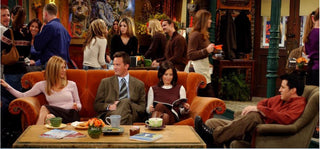 A still shot from the TV show Friends showing all the friends sitting at the coffee shop on the famous Friends couch