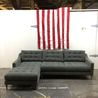A grey sofa chaise sectional with tufted buttoning