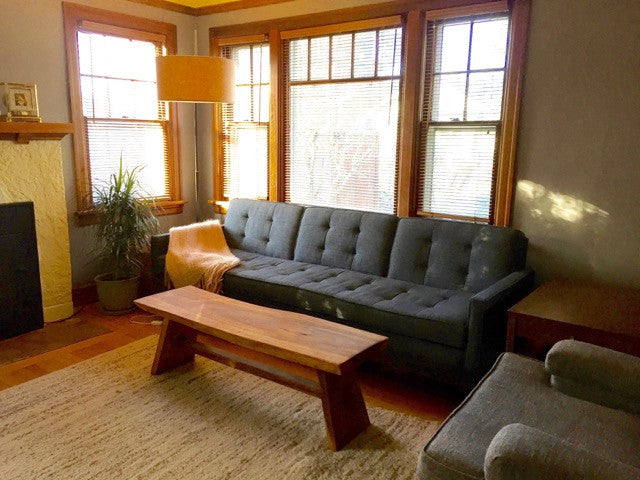 Grey sterling sofa couch in a modern living room with a wooden coffee table in front.