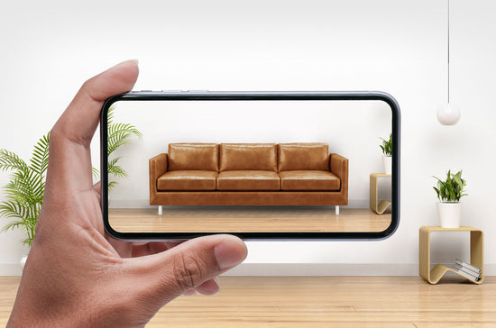 A hand holding a phone displaying a couch
